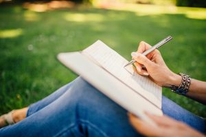person writing in journal outside